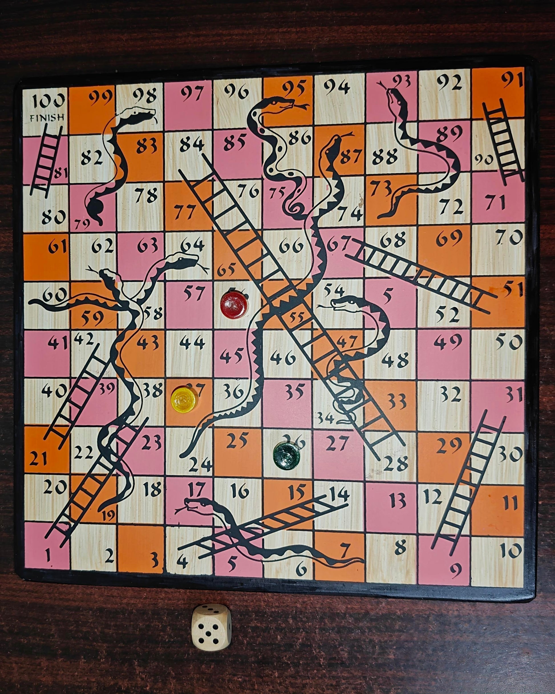 Snakes and Ladders game board on a wooden surface