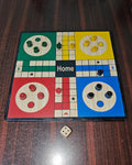 Ludo board game on a wooden surface with pieces and a dice.